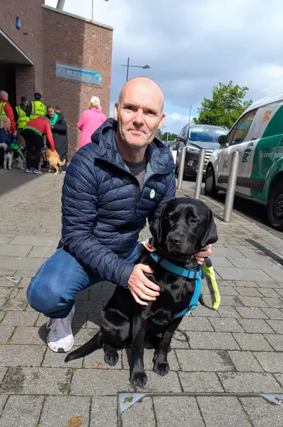 David kneeling down on a pavement with Tori sitting beside him