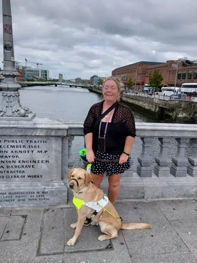 Yvonne standing on a bridge with Sammy sitting in front