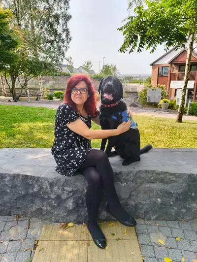 Rebecca sitting on a wall with Aslan sitting