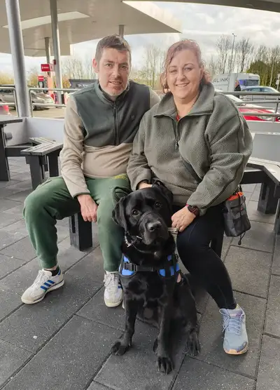 Róisín and James sitting on a bench with Otter sitting in front of them