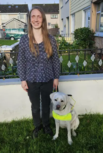 Shea standing in a garden with Bonnie sitting beside her.
