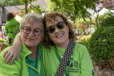 Two volunteers with arms around each other smiling at the camera