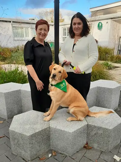 Anne and Alma standing in a garden with Elm sitting in front of them
