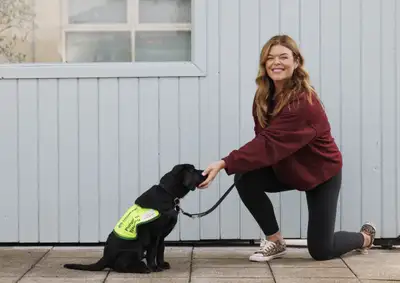 Doireann kneeling down giving a treat to Rufus who is sitting in front of her
