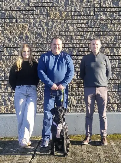 Claire, Kevin and Keith standing in front of a wall with Aria sitting in front