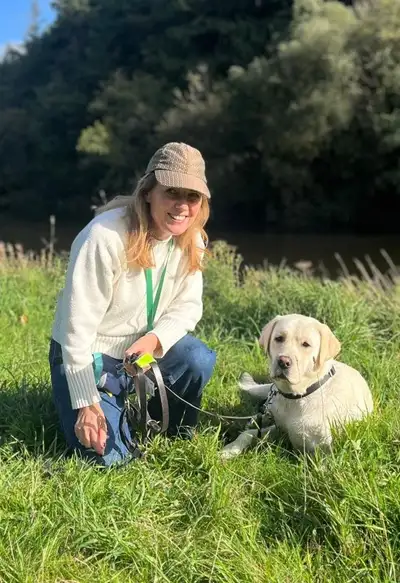 Suzanne kneeling in grass with Winstown lying down beside her