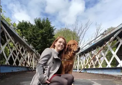 Sarah sitting with Guide Dog Mossy on a bridge